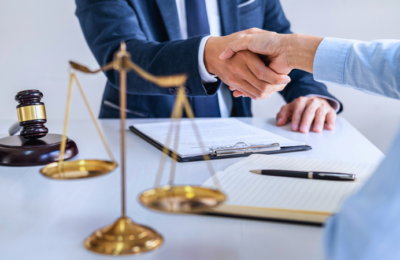 Two people shaking hands, judge gavel in background