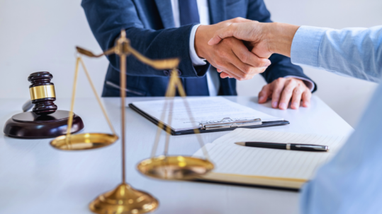 Two people shaking hands, judge gavel in background